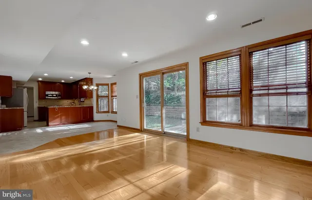 a view of an empty room with a window and a kitchen area