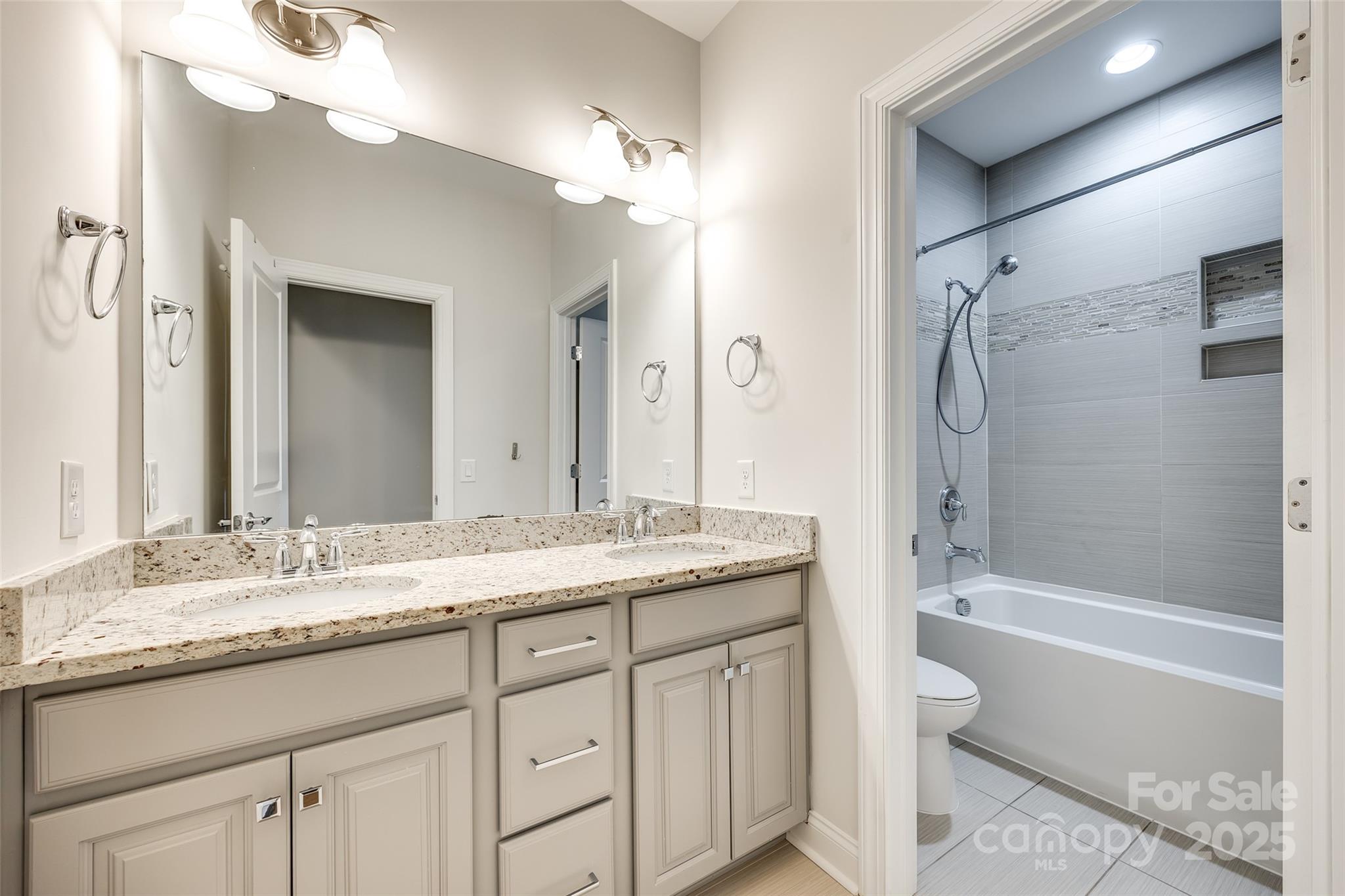 1056 Emory Lane Fort Mill, SC 29708 - Photo 30 of 48 a bathroom with a granite countertop sink a toilet a mirror a bathtub and shower