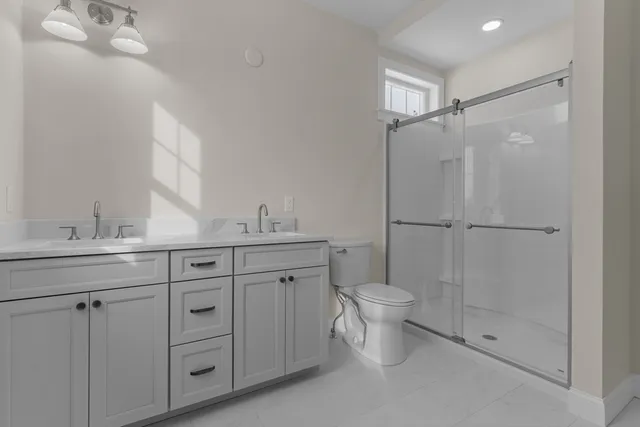 a bathroom with a double vanity sink toilet mirror and shower