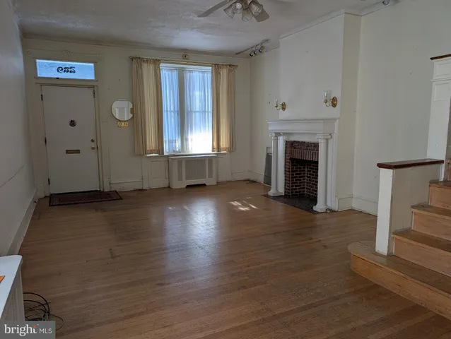 an empty room with windows fireplace and wooden floor