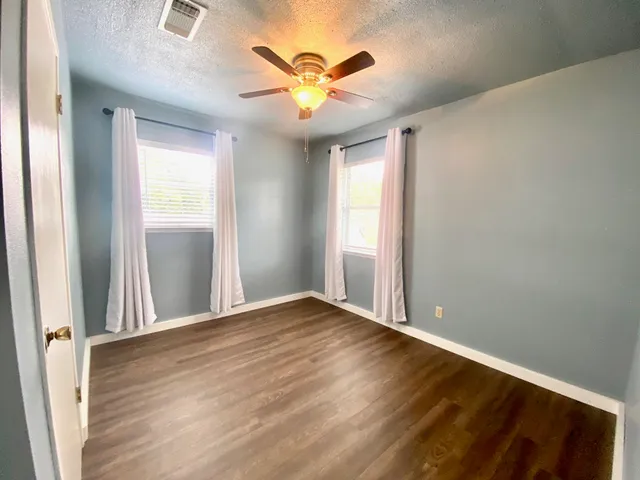 an empty room with window and ceiling fan