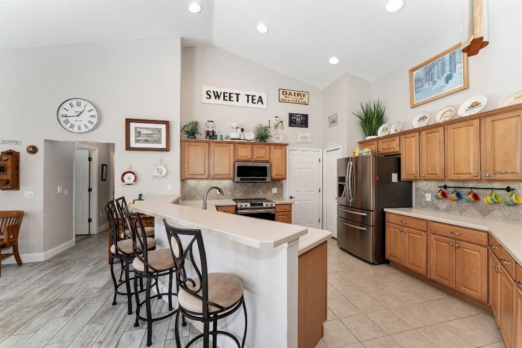 19115 Southwest 98th Loop Dunnellon, FL 34432 - Photo 12 of 36 a kitchen with stainless steel appliances a stove top oven a refrigerator a dining table and chairs with wooden floor