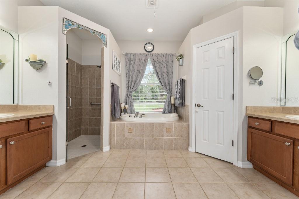 19115 Southwest 98th Loop Dunnellon, FL 34432 - Photo 21 of 36 a bathroom with a granite countertop sink a mirror and a bathtub