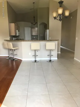 a living room with couches chairs and kitchen view with wooden floor