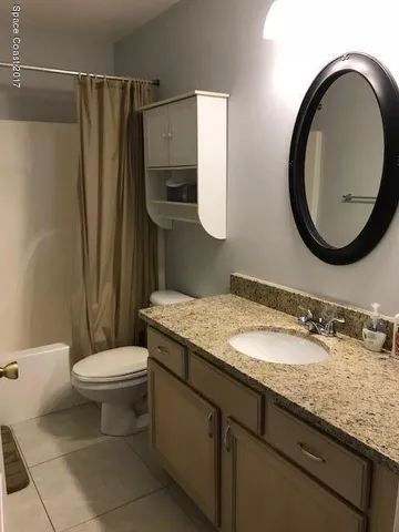 a bathroom with a granite countertop toilet sink and mirror