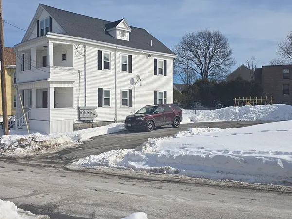 a front view of a house with a snow on the road