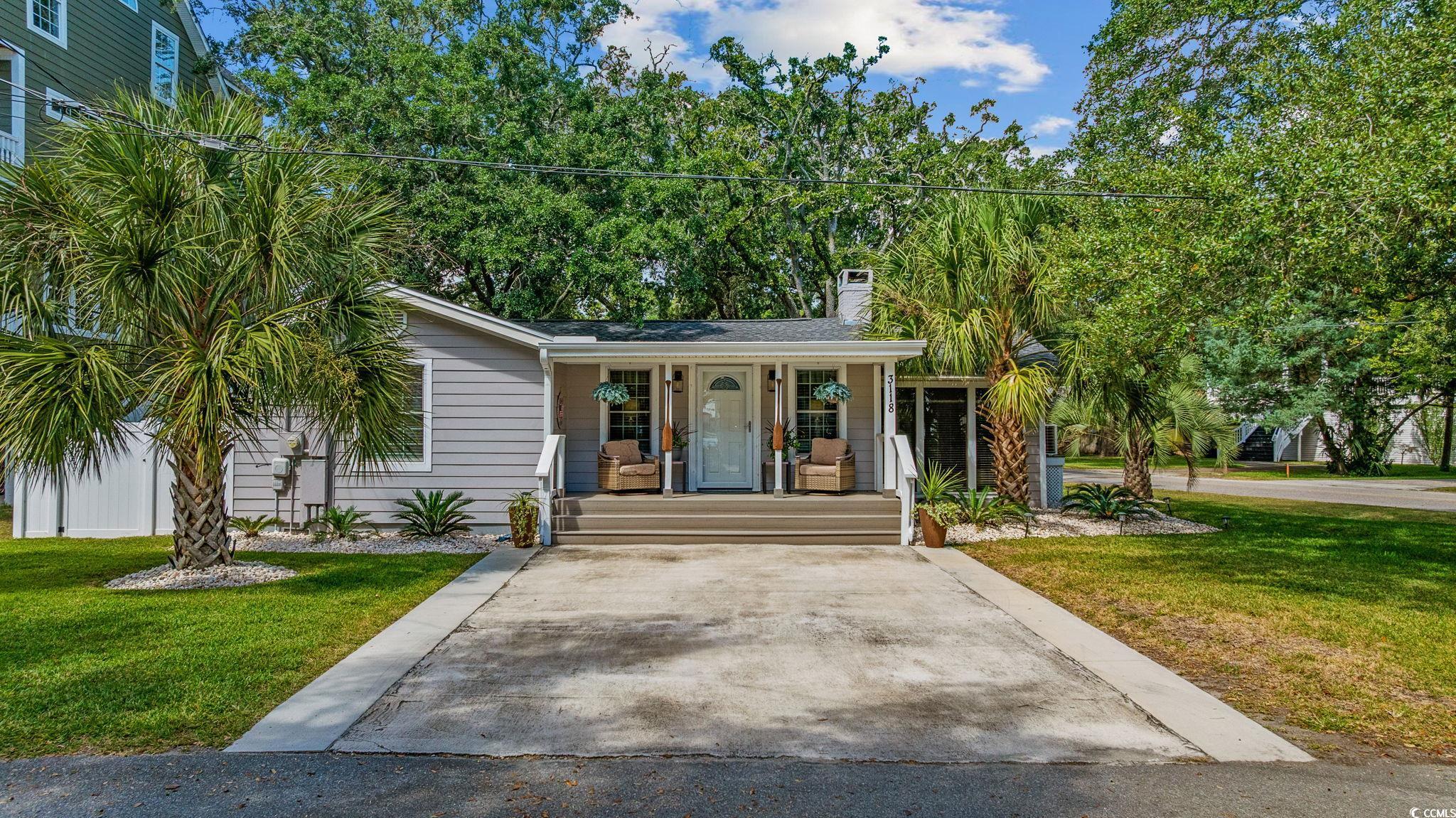 View of front of home with a front lawn, covered porch, and a chimney