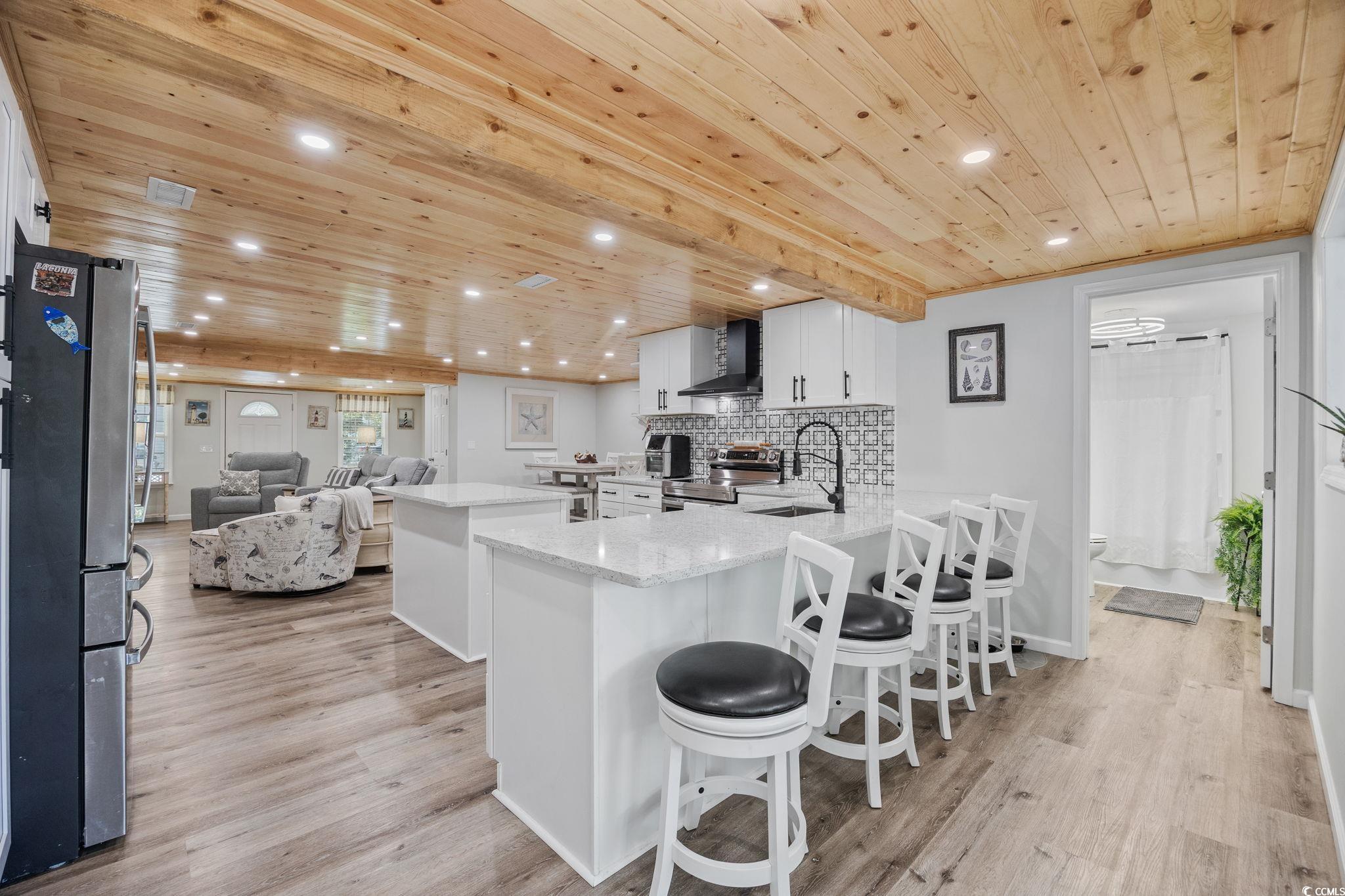 3118 State Rd S-26-816 Murrells Inlet, SC 29576 - Photo 5 of 40 Kitchen with a kitchen island, wooden ceiling, white cabinetry, a kitchen breakfast bar, and stainless steel appliances