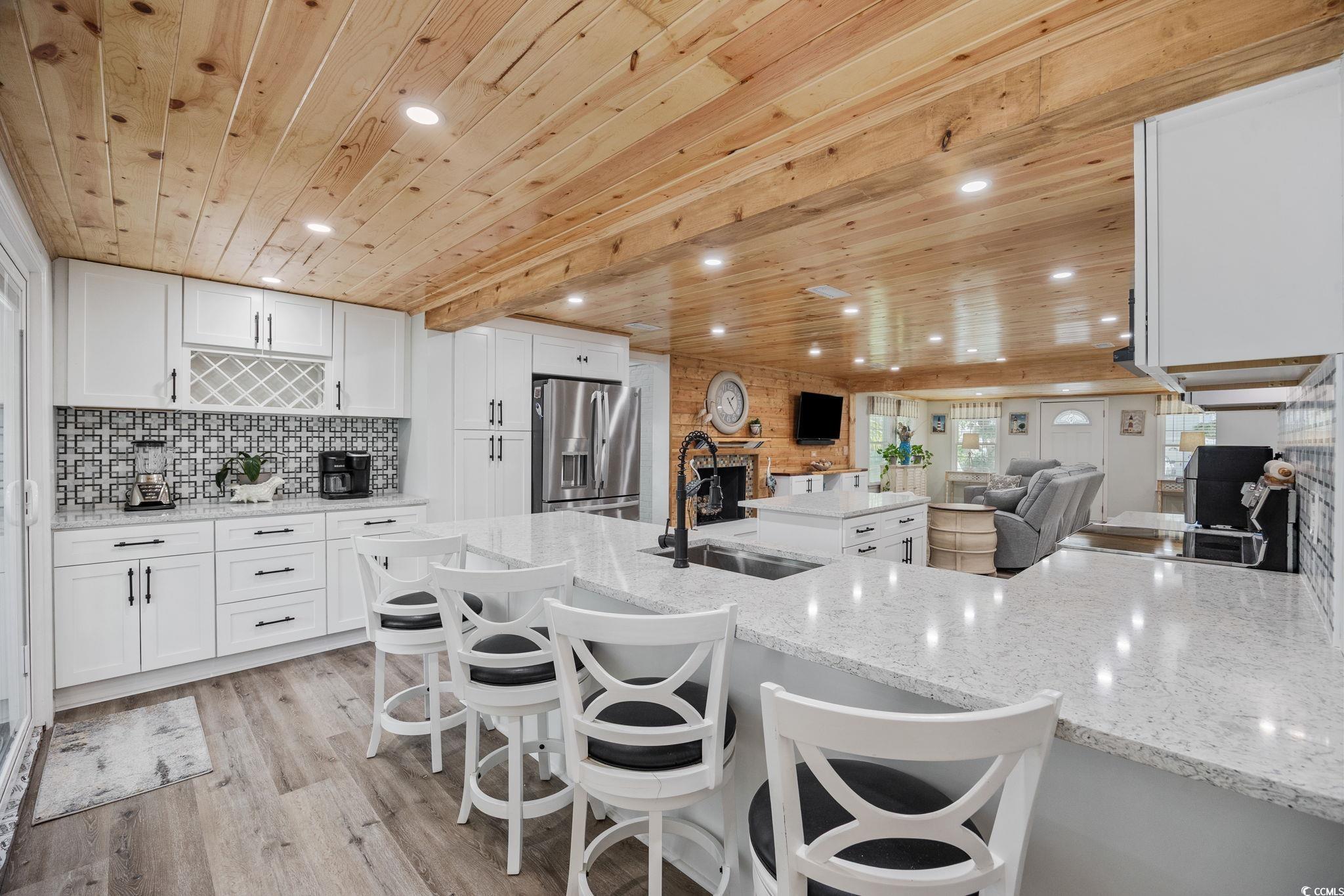 3118 State Rd S-26-816 Murrells Inlet, SC 29576 - Photo 6 of 40 Kitchen with white cabinetry, wood ceiling, stainless steel refrigerator with ice dispenser, light stone countertops, and light wood-style floors
