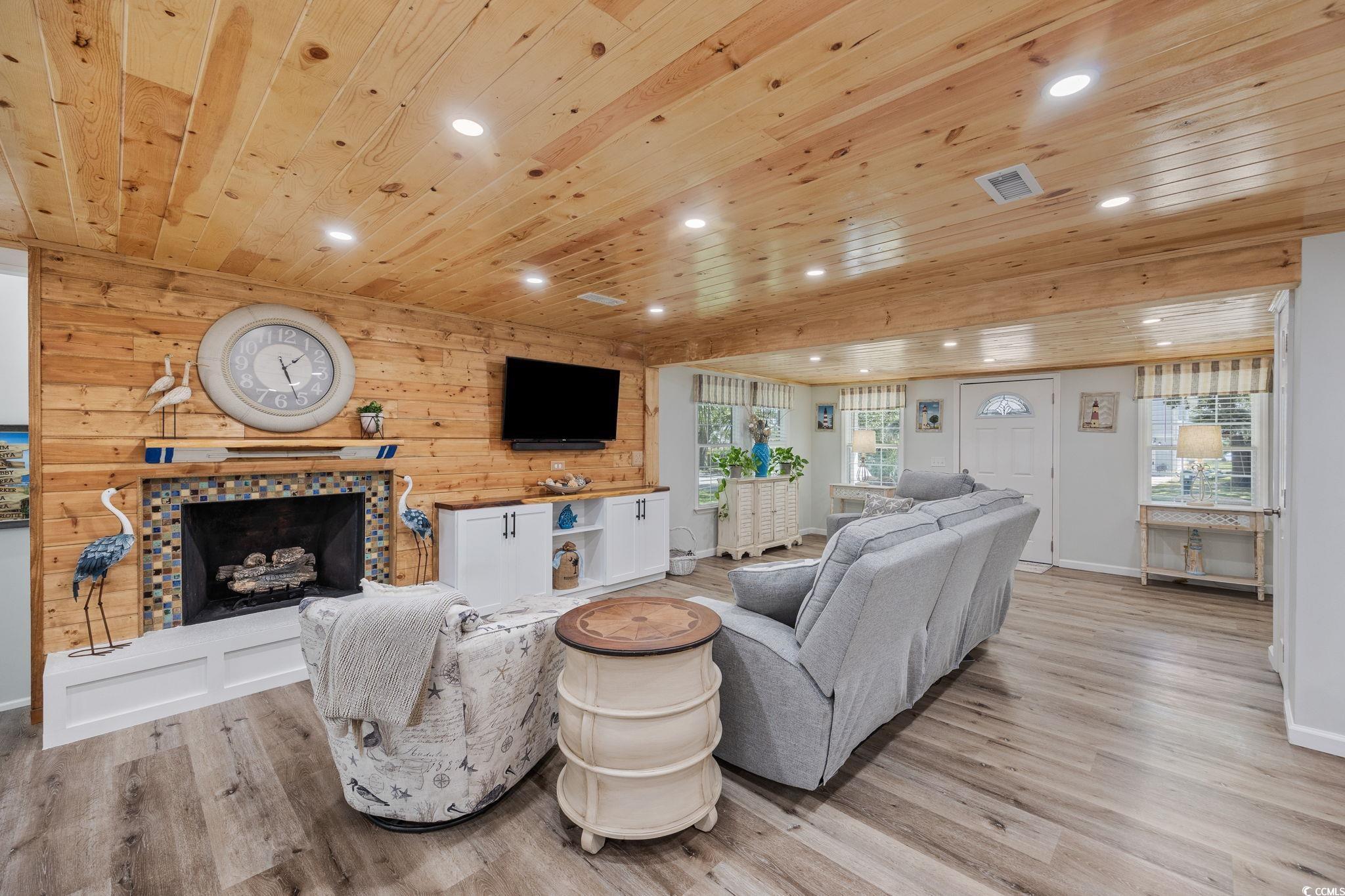 3118 State Rd S-26-816 Murrells Inlet, SC 29576 - Photo 9 of 40 Living area with healthy amount of natural light, wooden walls, light wood finished floors, a tile fireplace, and wooden ceiling