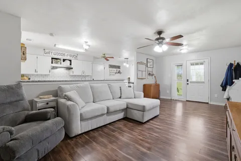 a view of a living room a wooden floor and a ceiling fan