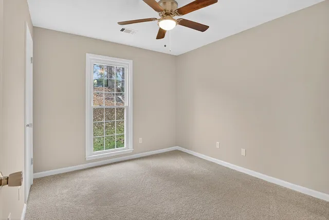 an empty room with a window and a fan