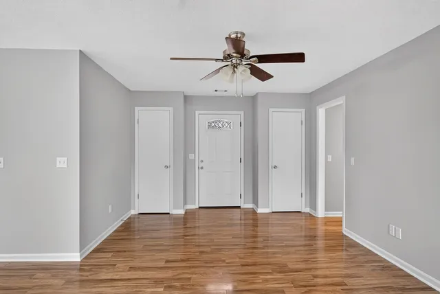 a view of a room with wooden floor and ceiling fan