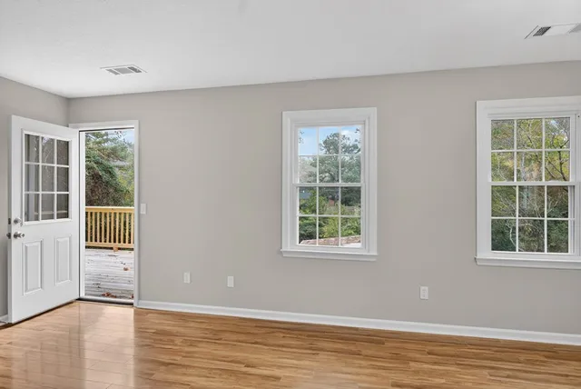an empty room with wooden floor and windows