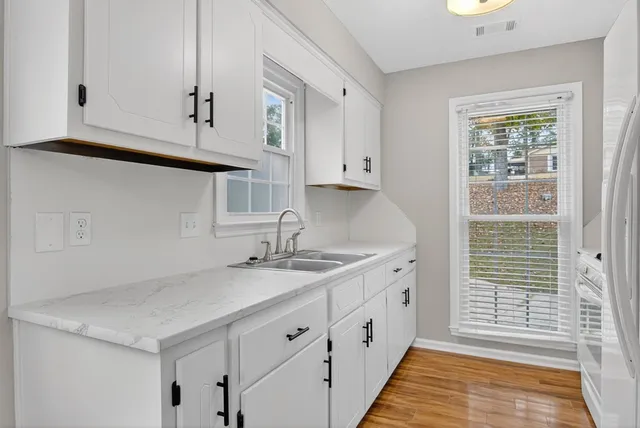 a kitchen with granite countertop white cabinets and sink