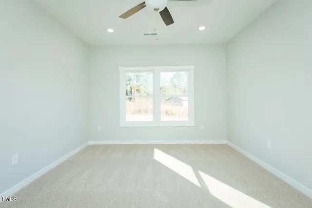 an empty room with a window and a fan