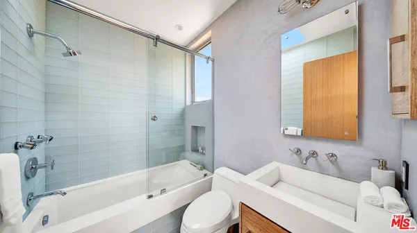 a bathroom with a bathtub shower sink mirror vanity and a toilet