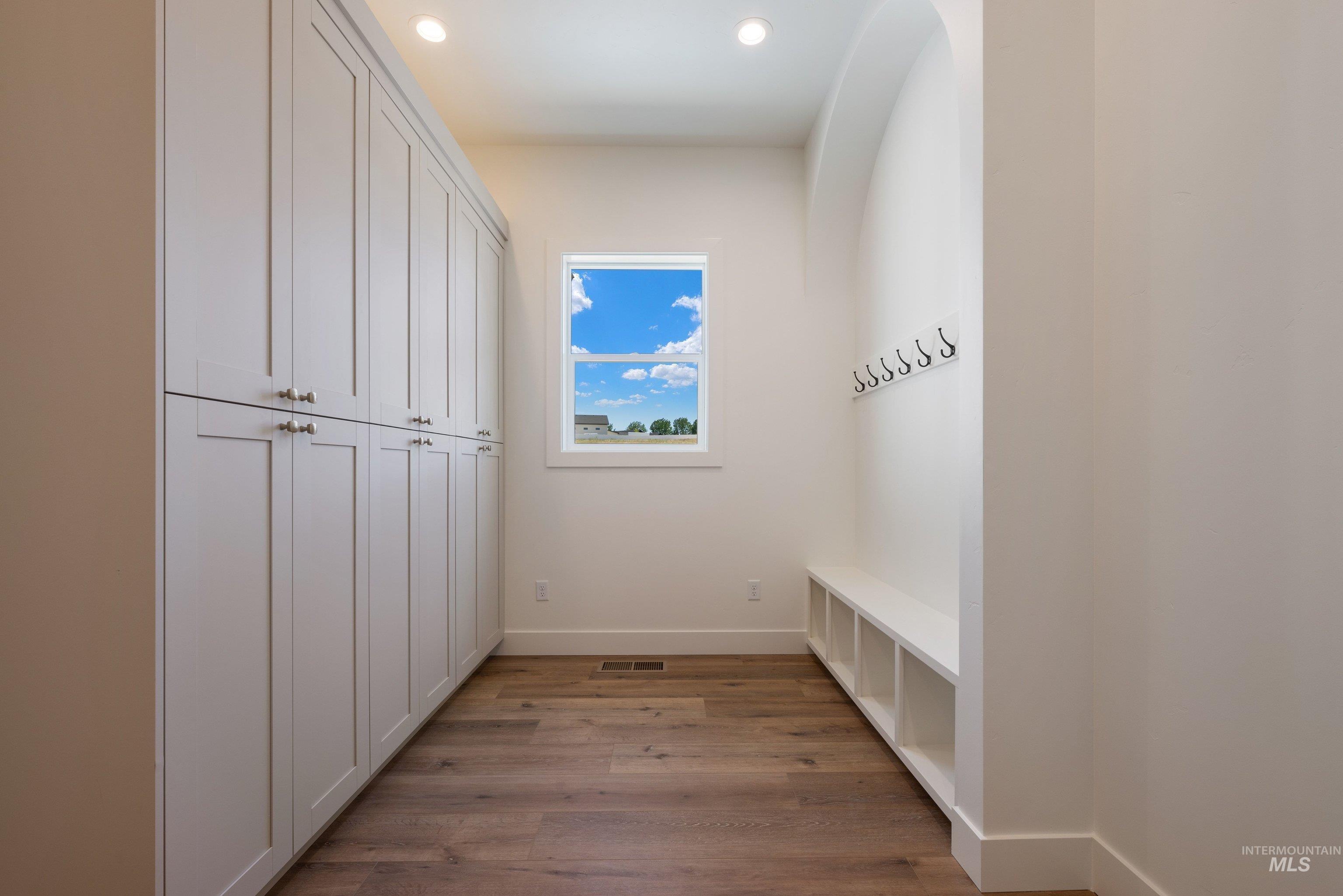 24821 Ardmore Court Caldwell, ID 83607 - Photo 29 of 43 Entryway mudroom featuring extensive built-in cabinetry, wood-finish flooring, recessed lighting, a built-in bench with cubby storage, and wall-mounted coat hooks