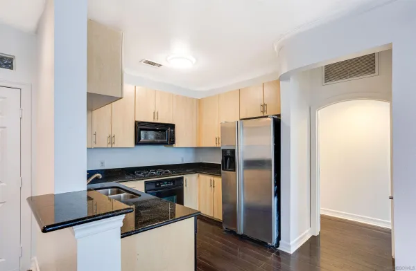 a kitchen with granite countertop a refrigerator and a stove top oven