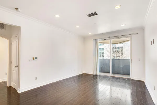 a view of an empty room with wooden floor and a window