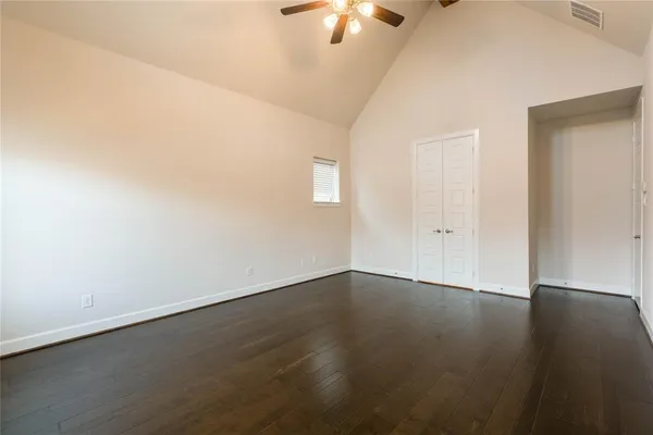 an empty room with wooden floor chandelier fan and windows