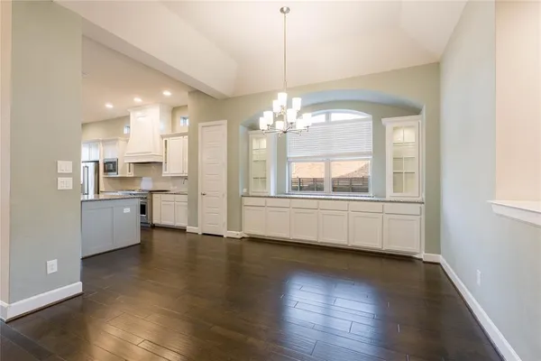 a view of a large kitchen with a window wooden floor and cabinets