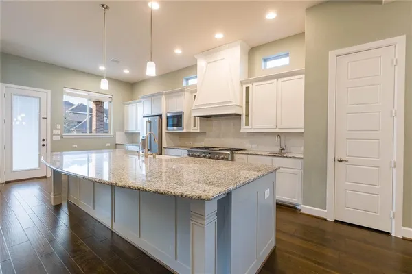 a kitchen with stainless steel appliances granite countertop a sink a stove and a wooden floors