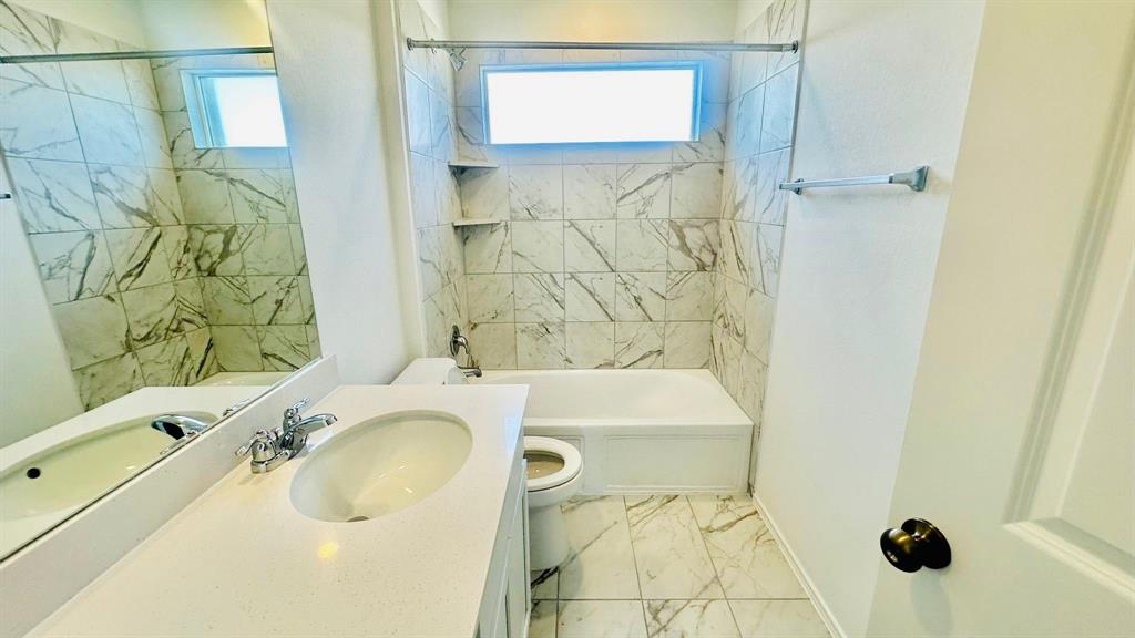 192 Rodney Boat Road Kyle, TX 78640 - Photo 30 of 38 White marble tile and a pristine vanity create a serene bath retreat.