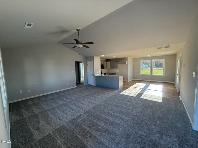 a view of an empty room and window and a kitchen