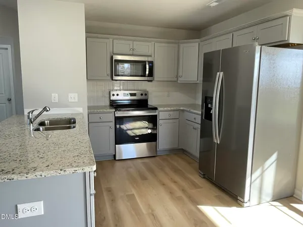 a kitchen with granite countertop a refrigerator and a sink