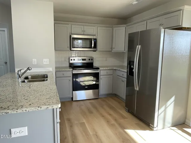 a kitchen with granite countertop a refrigerator and a sink