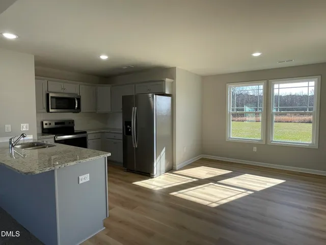 a kitchen with granite countertop a refrigerator and a stove top oven