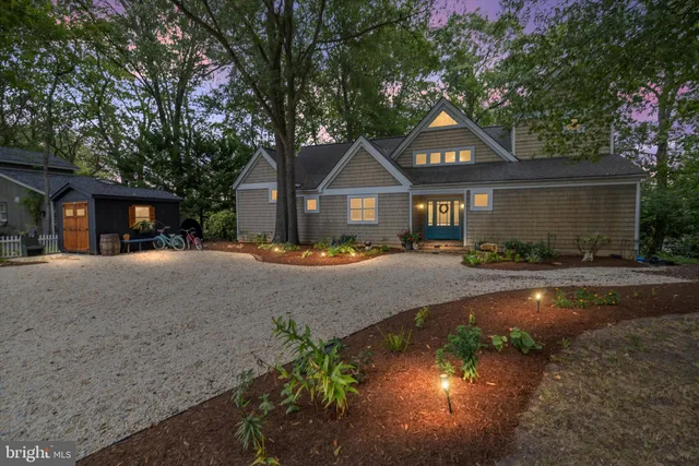 a front view of a house with a yard and large trees