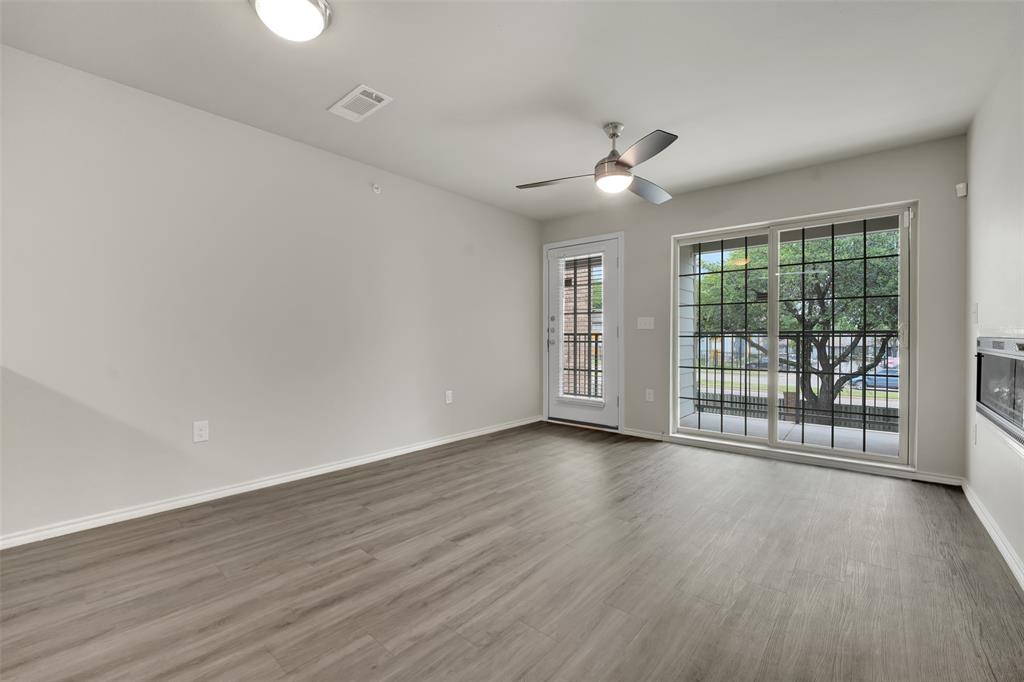 6108 Abrams Road, Unit 211 Dallas, TX 75231 - Photo 5 of 18 an empty room with wooden floor and windows