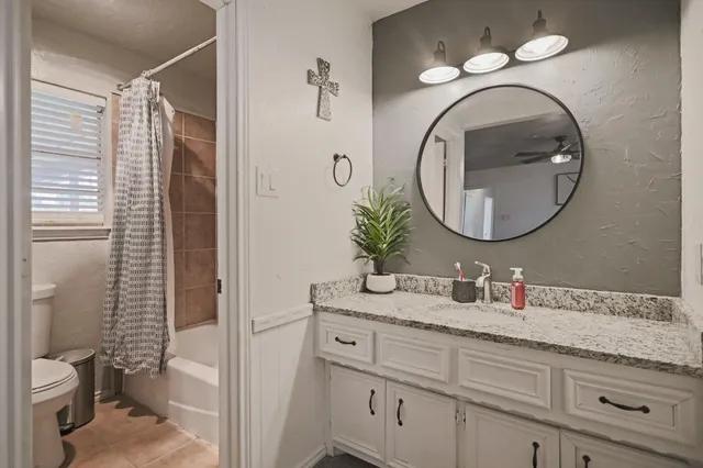 a bathroom with a granite countertop toilet sink and mirror
