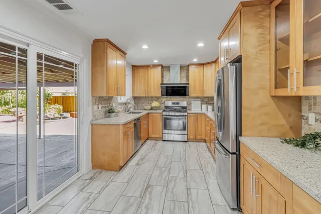 a kitchen with stainless steel appliances granite countertop a stove top oven a sink dishwasher a refrigerator and white cabinets with wooden floor