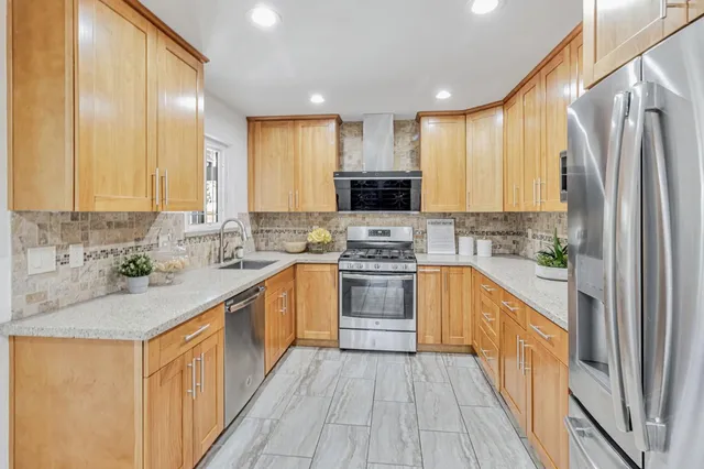 a kitchen with stainless steel appliances granite countertop a stove a sink and a refrigerator
