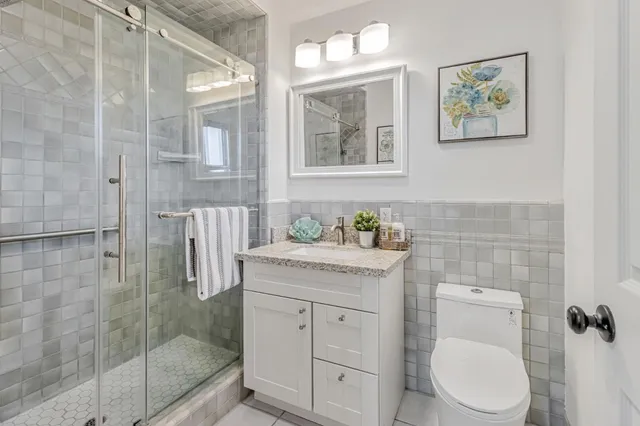 a bathroom with a granite countertop toilet sink and mirror