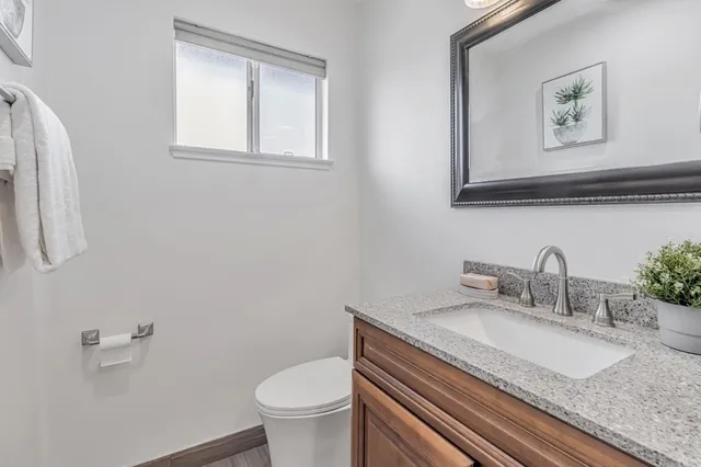 a bathroom with a granite countertop sink and a toilet