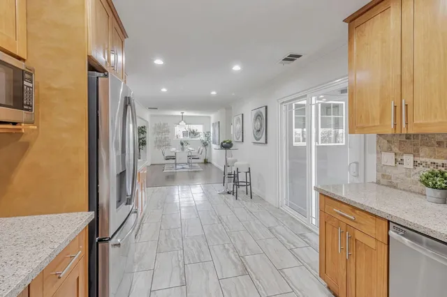 a kitchen with stainless steel appliances granite countertop a refrigerator a sink dishwasher and a stove with wooden floor