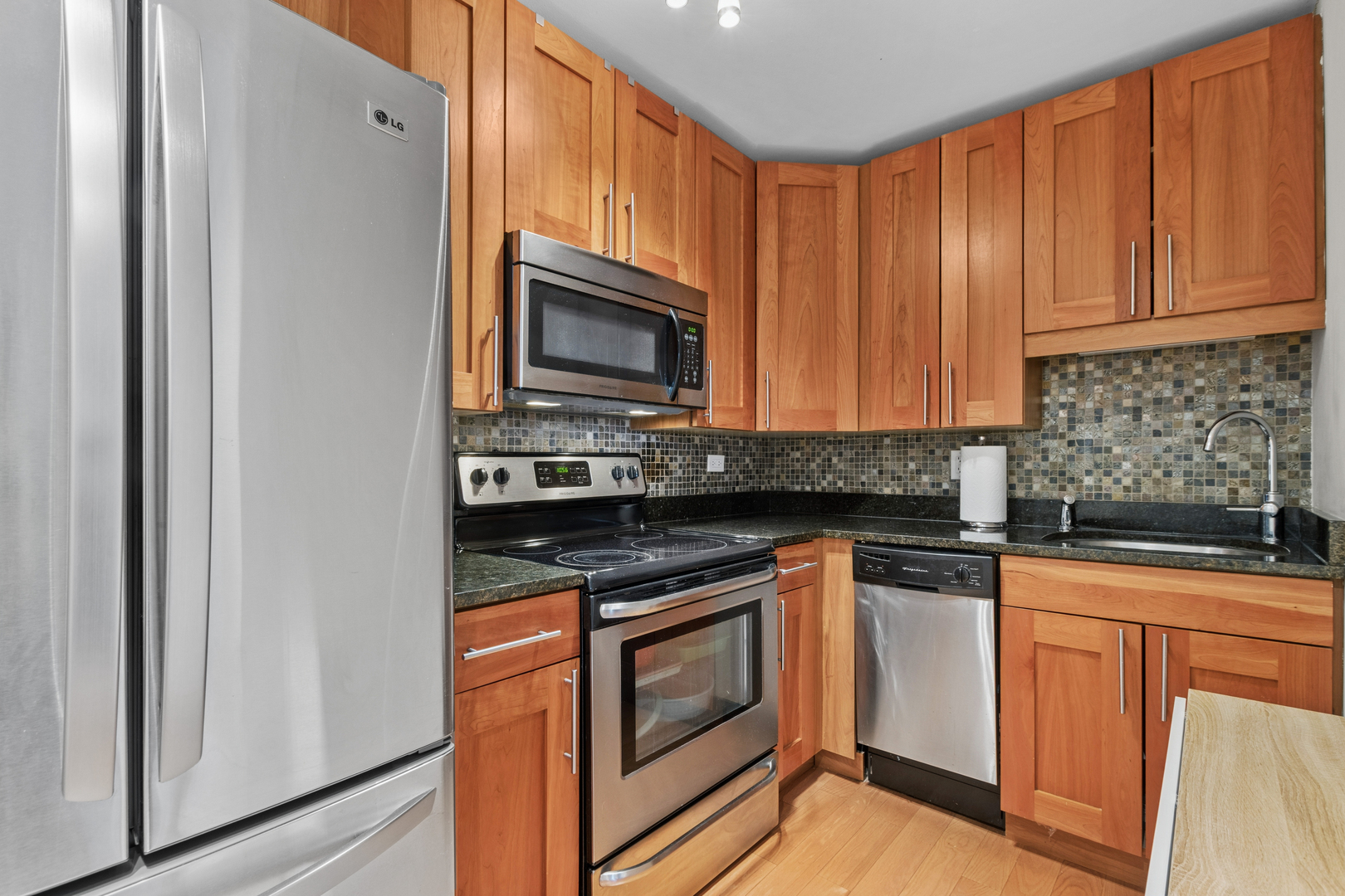 3033 North Sheridan Road, Unit 1502 Chicago, IL 60657 - Photo 6 of 19 a kitchen with granite countertop stainless steel appliances a stove microwave and refrigerator