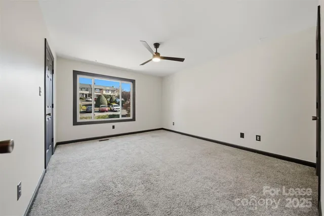 an empty room with windows and ceiling fan