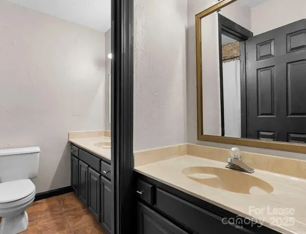 a bathroom with a granite countertop sink and a toilet