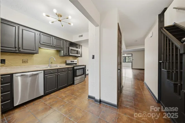 a kitchen with granite countertop a sink cabinets and stainless steel appliances
