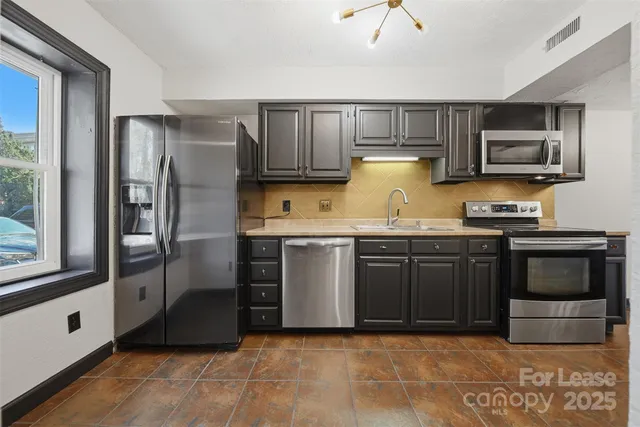 a kitchen with granite countertop a refrigerator and a stove top oven