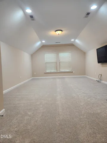 an empty room with wooden floor and flat screen tv