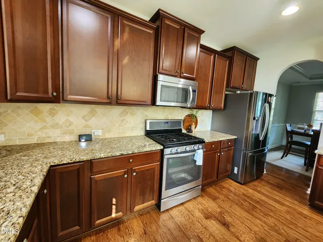 a kitchen with granite countertop wooden cabinets stainless steel appliances and a counter space