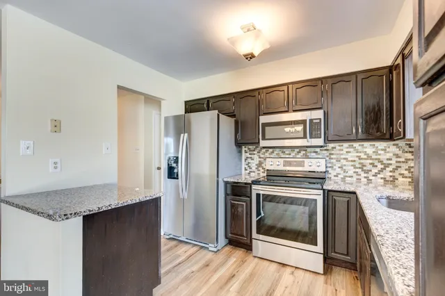 a kitchen with granite countertop a refrigerator stove and sink