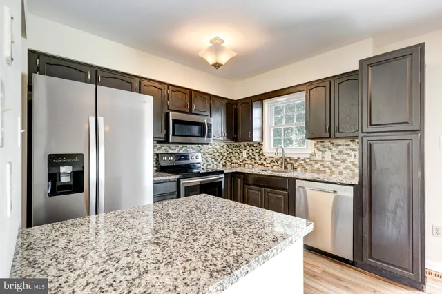 a kitchen with stainless steel appliances granite countertop refrigerator stove microwave and sink