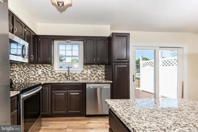 a kitchen with stainless steel appliances kitchen island granite countertop a refrigerator and a stove top oven
